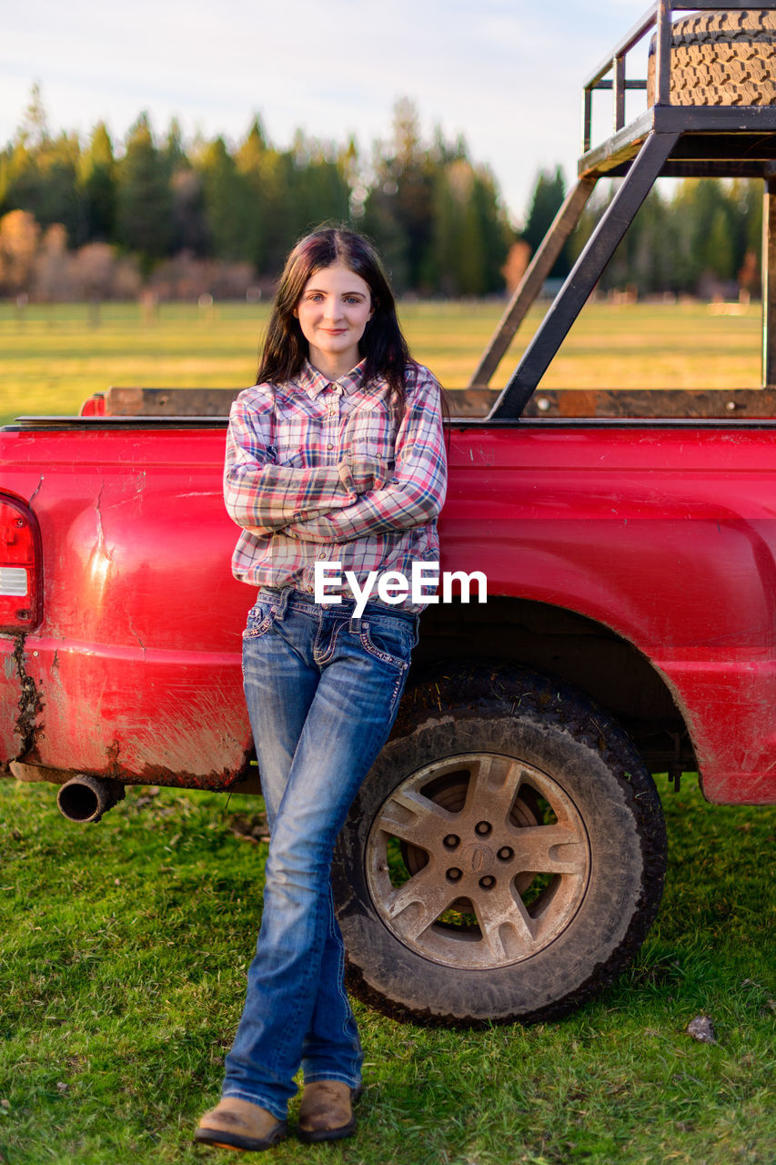 Portrait of young woman leaning against truck 