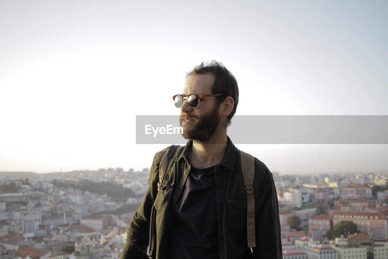 Man looking away while standing against clear sky