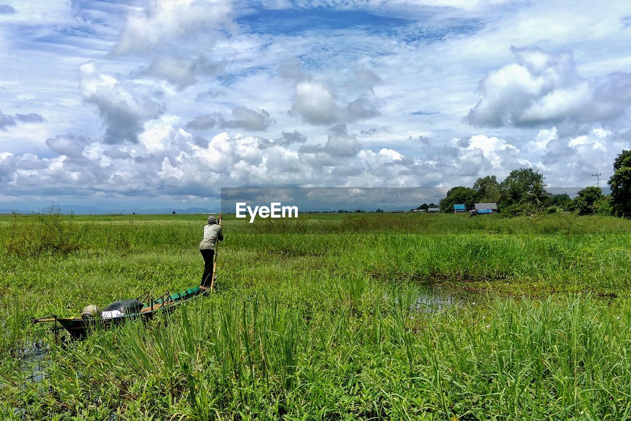 Man working on field against cloudy sky