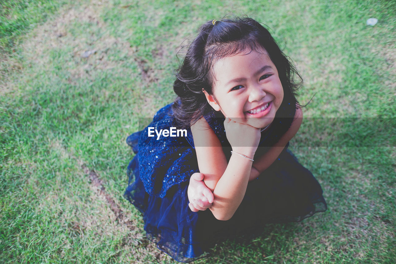 Portrait of smiling girl on grassy field at public park