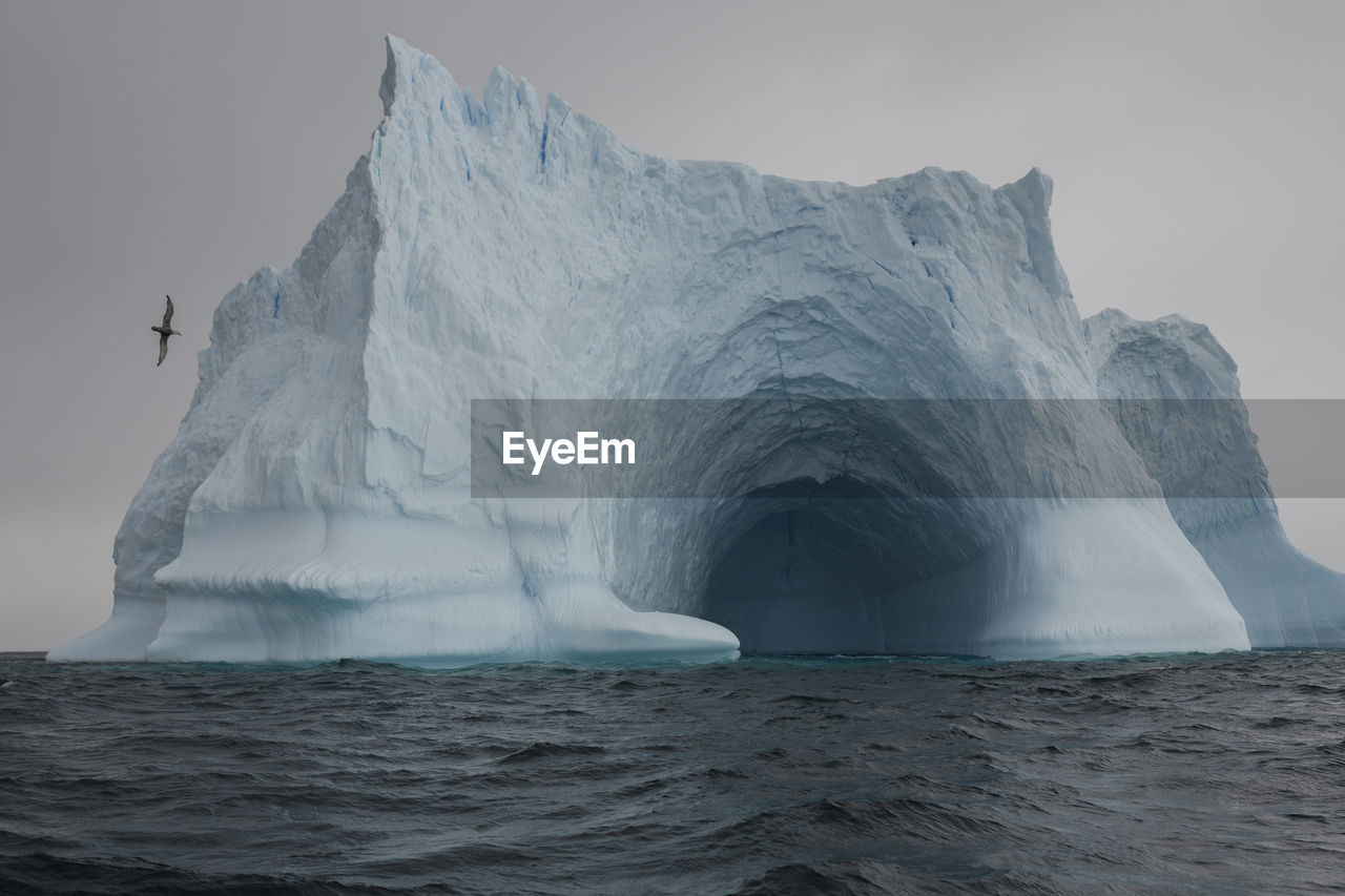 Scenic view of ice cave in sea against sky during winter