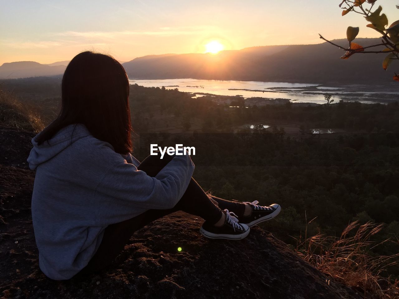 Rear view of woman looking at lake and mountains during sunset