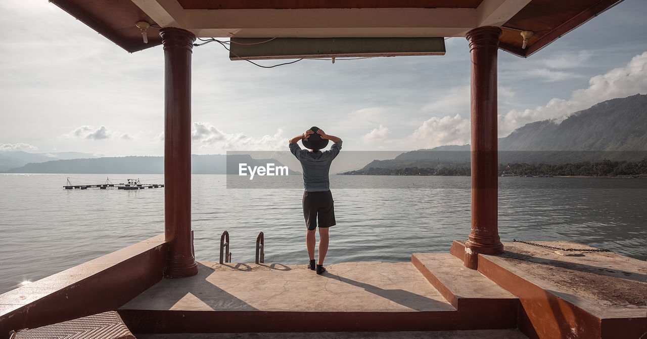 Full length rear view of woman standing on diving platform by lake