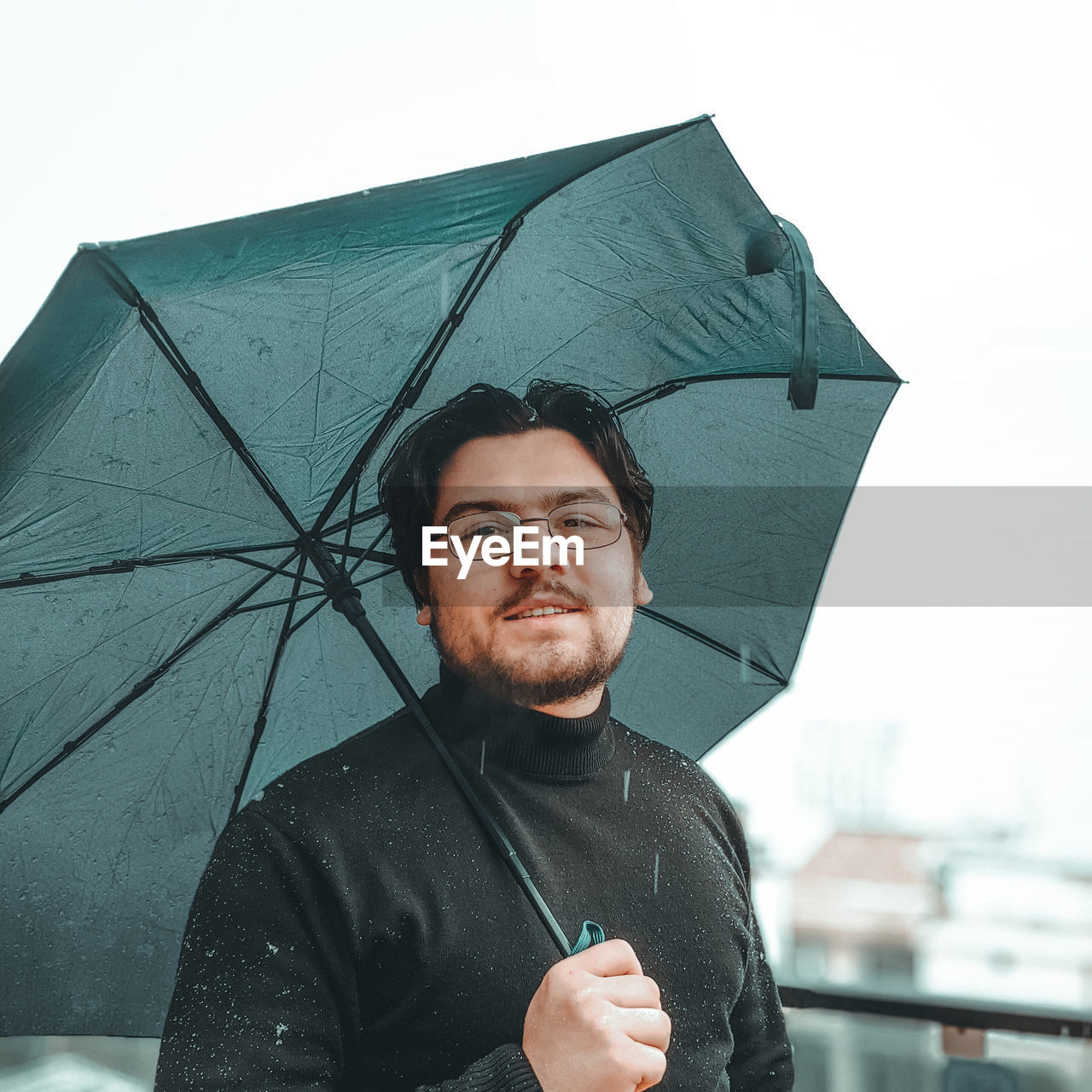 Portrait of man holding umbrella standing against sky