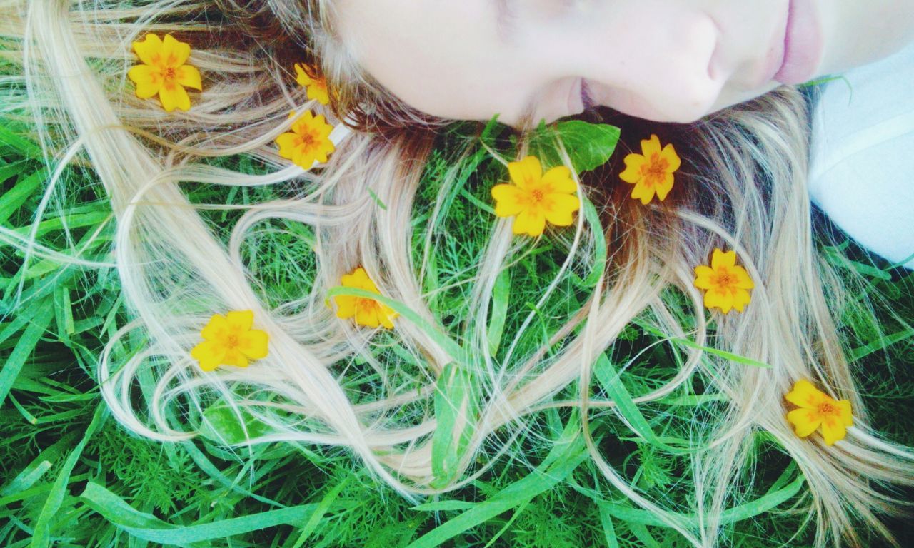 Cropped image of woman relaxing on grassy field with yellow flowers