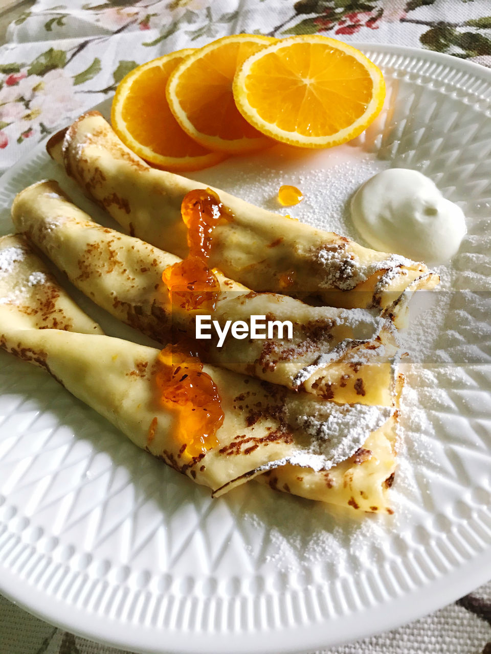 Beautifully served thin pancakes with orange jam and oranges