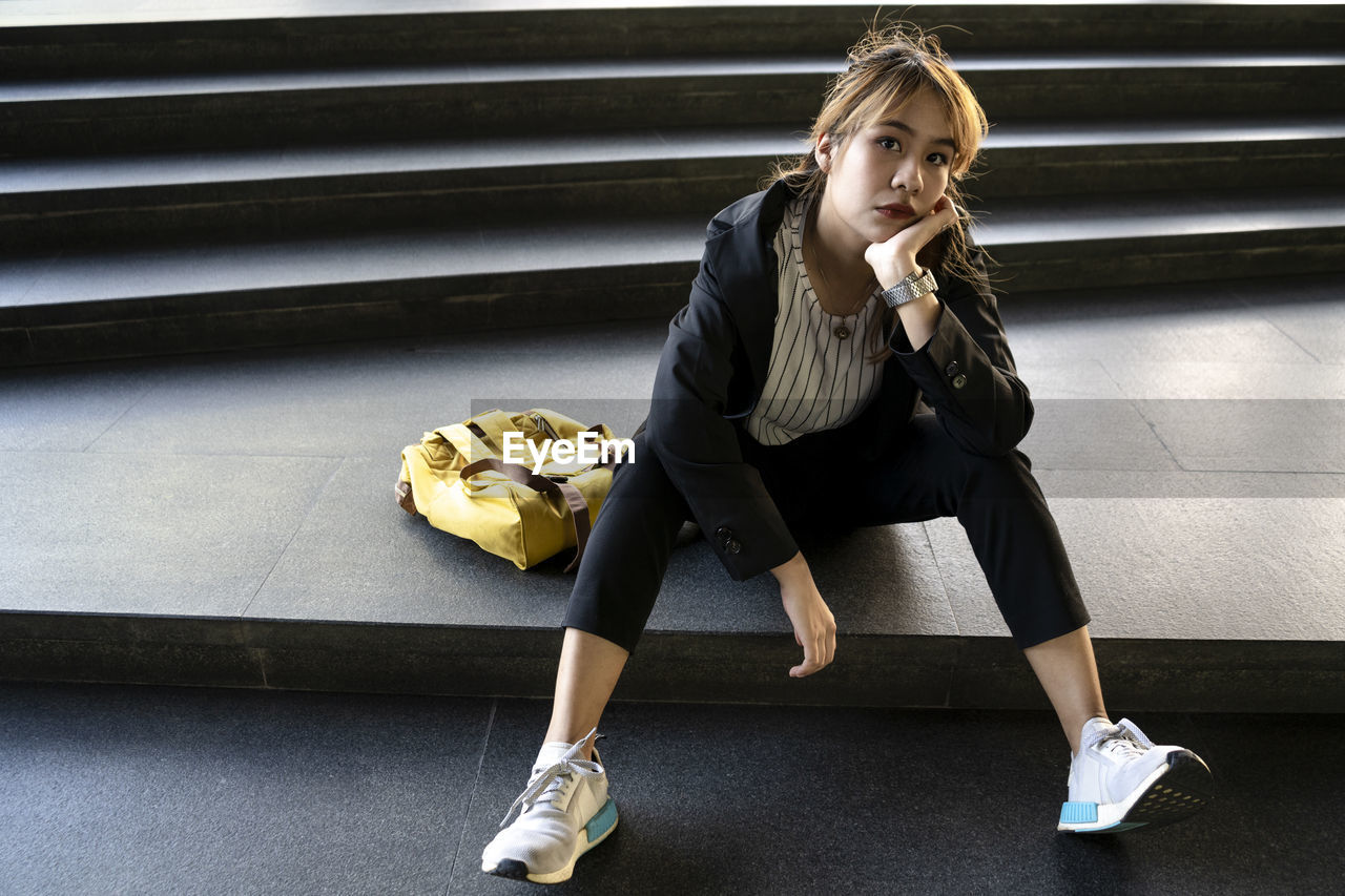 Portrait of businesswoman with backpack sitting on steps