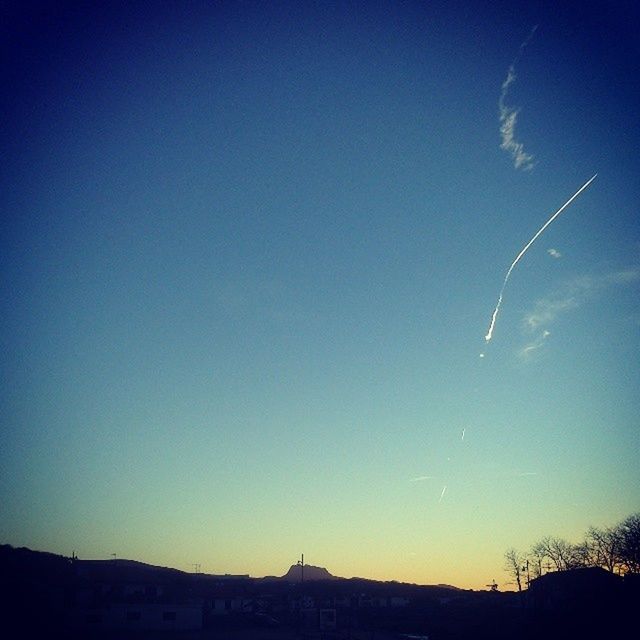 LOW ANGLE VIEW OF SILHOUETTE VAPOR TRAIL IN SKY