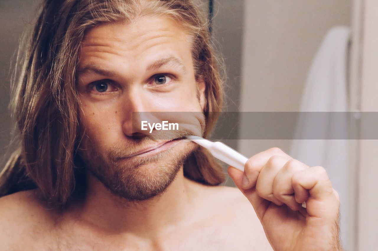 Close-up portrait of man brushing teeth