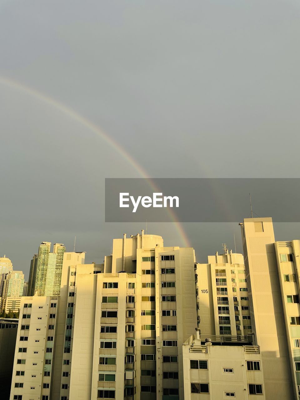Low angle view of rainbow over buildings against sky
