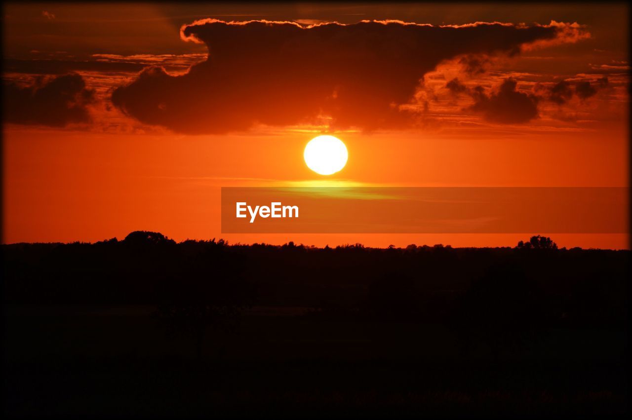 Silhouette landscape against orange sky