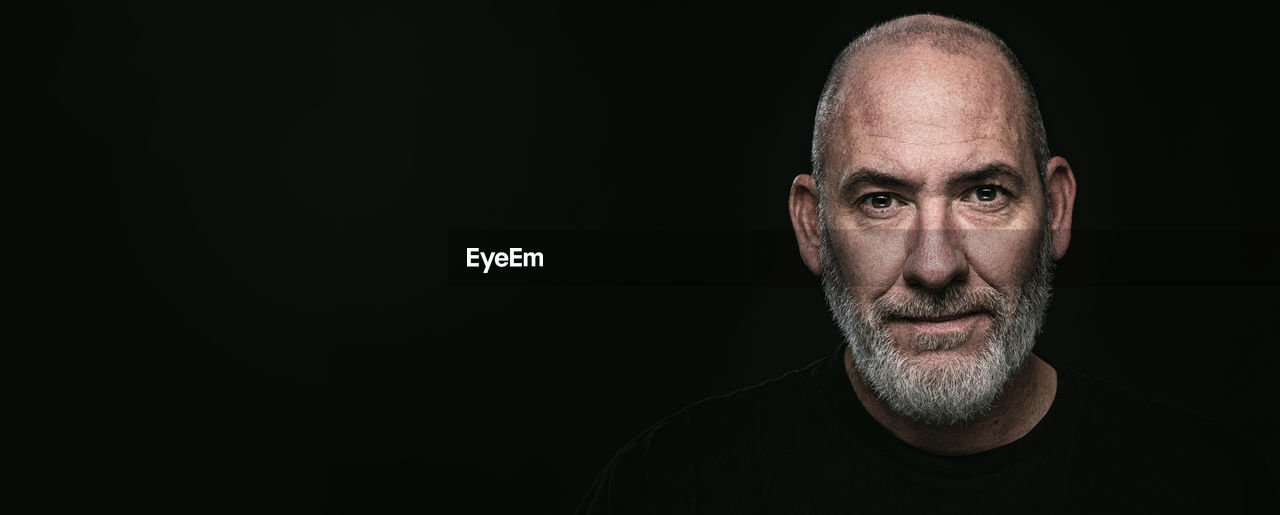 close-up portrait of man with eyes closed against black background