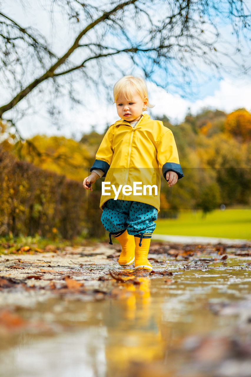 full length portrait of boy standing on puddle