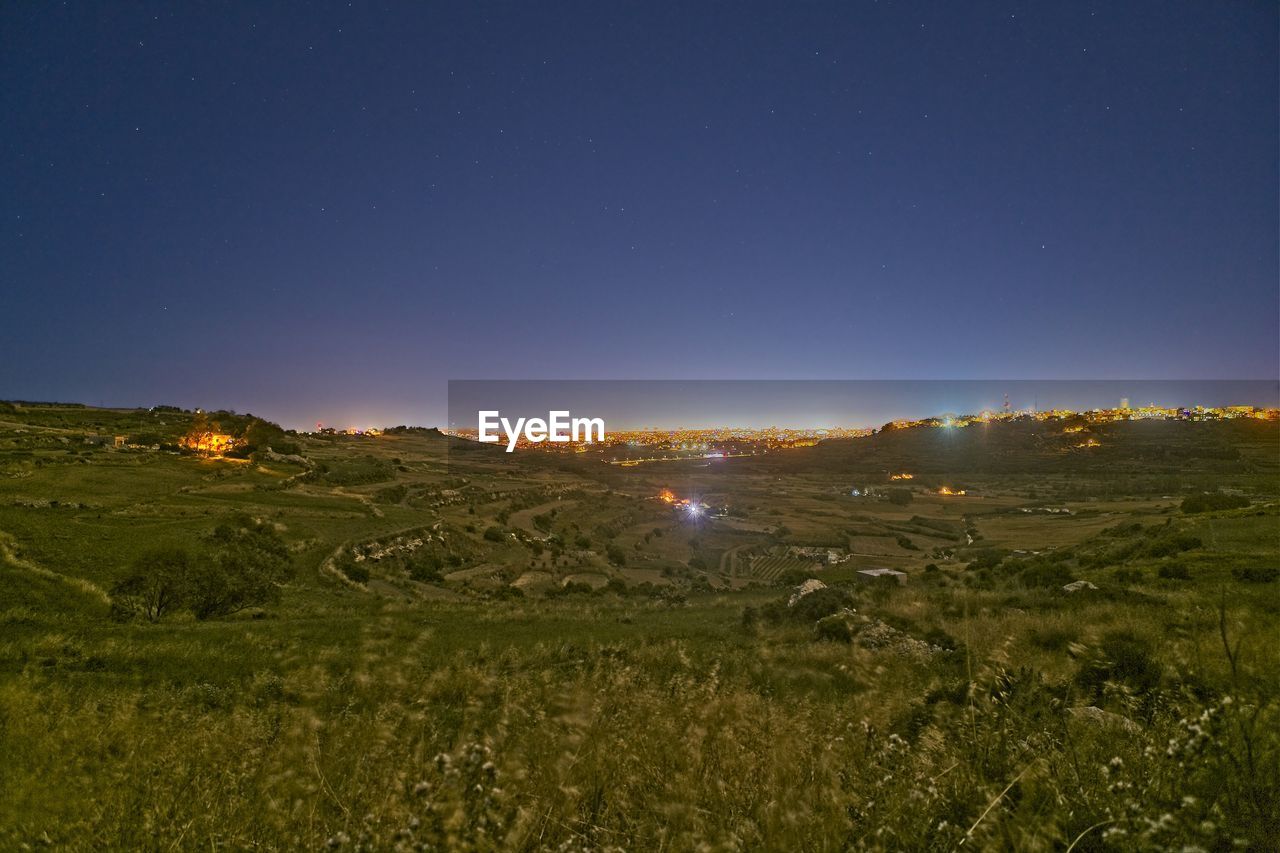 Scenic view of field against clear sky at night