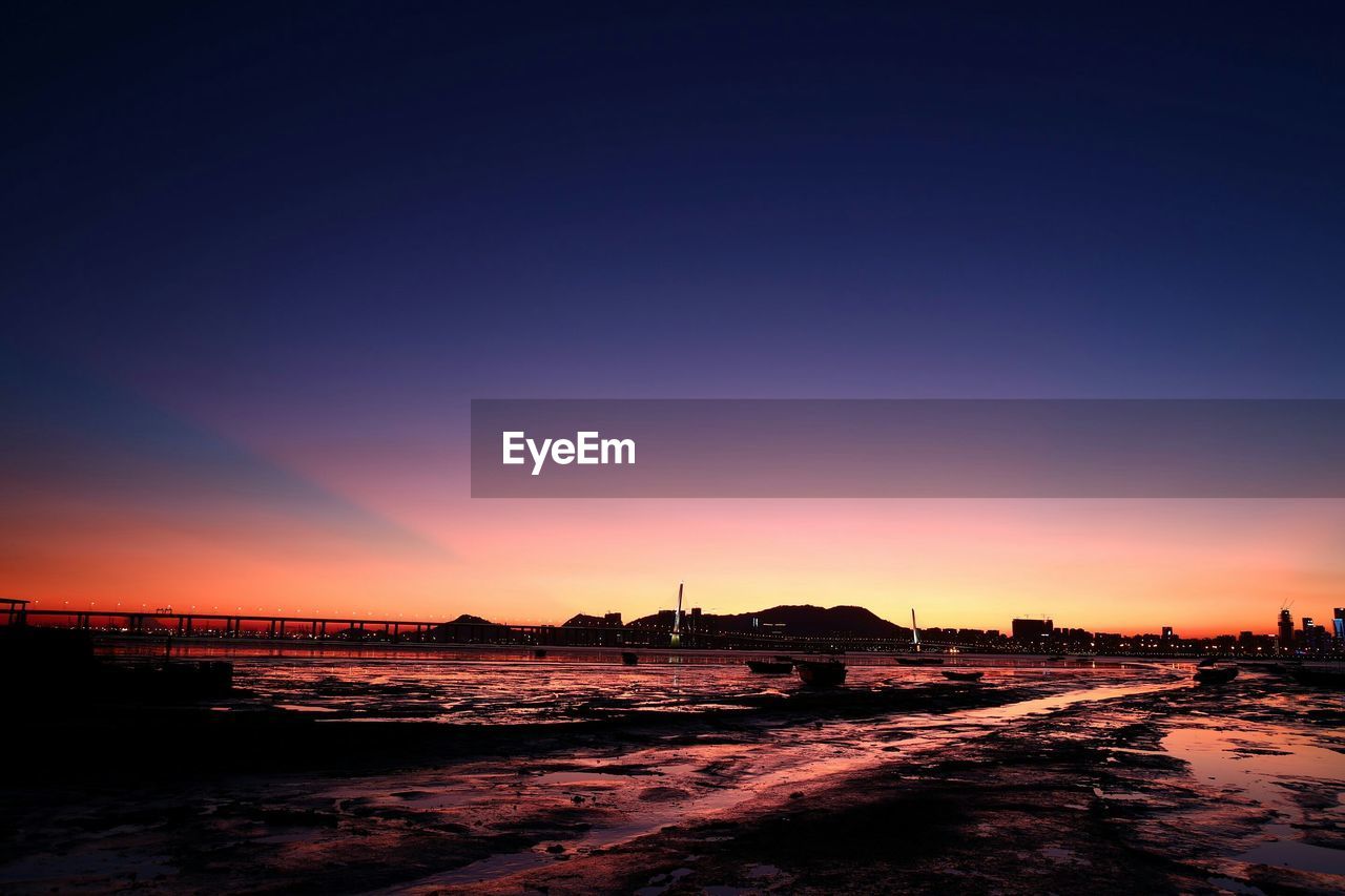 Bridge and sea against sky during sunset