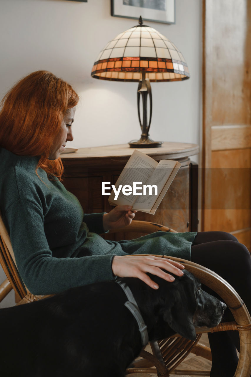 Woman on rocking chair reading book. relaxed home atmosphere. vintage house for slow living. female