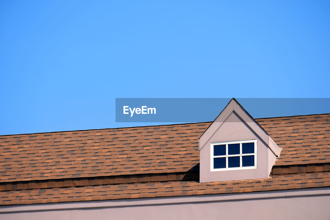 LOW ANGLE VIEW OF HOUSE ROOF AGAINST BLUE SKY