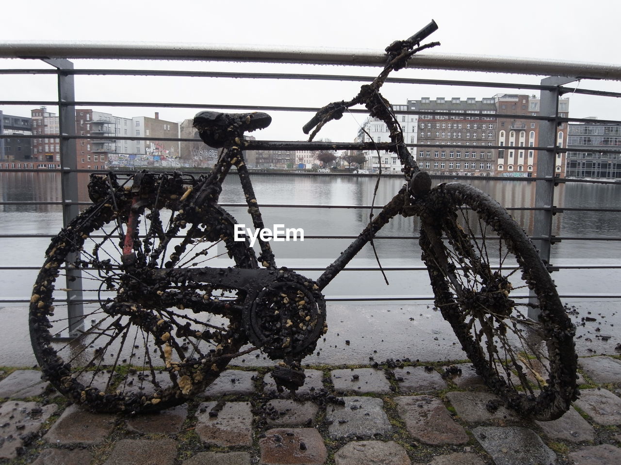 Muddy bicycle on footpath against river