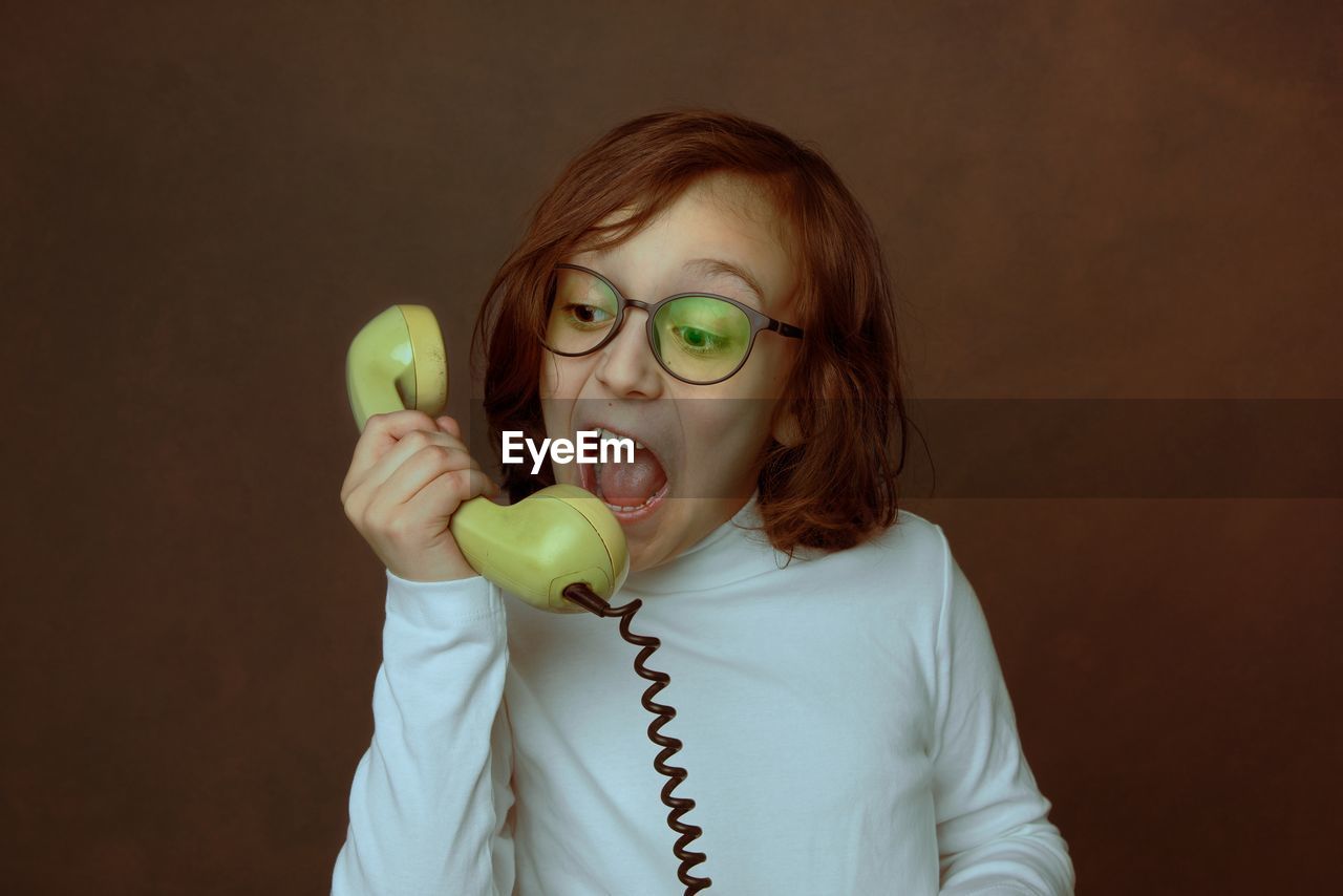 Portrait of a kid holding the wire phone, talking expressively. 