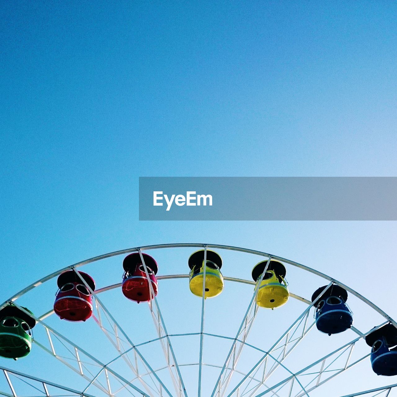 Low angle view of ferris wheel against clear blue sky