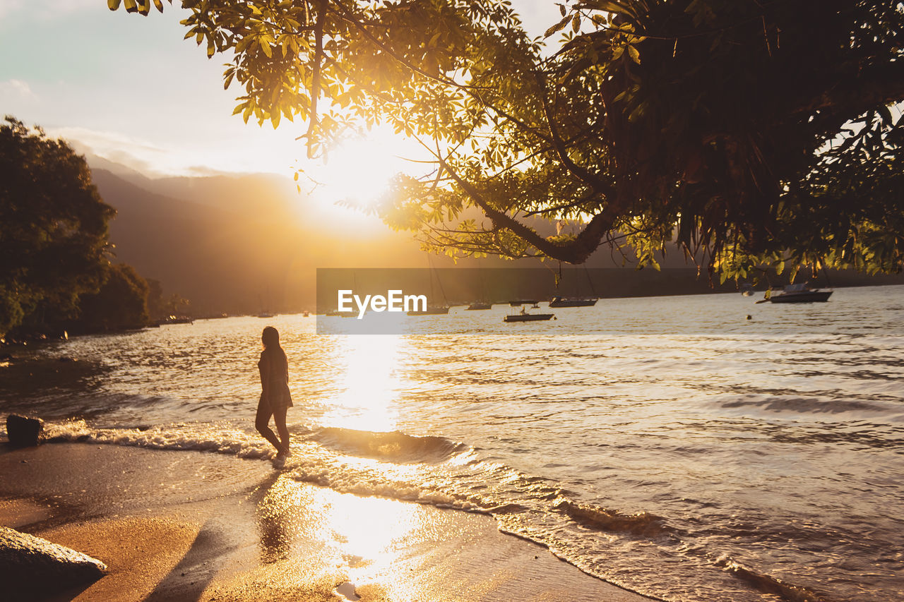 Scenic view of sea against sky during sunset. girl walking alone