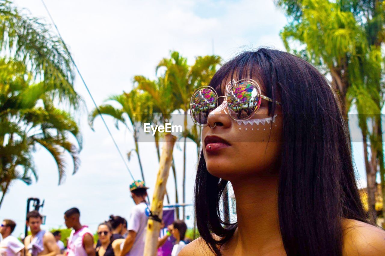 Woman in sunglasses with painted face during event in city