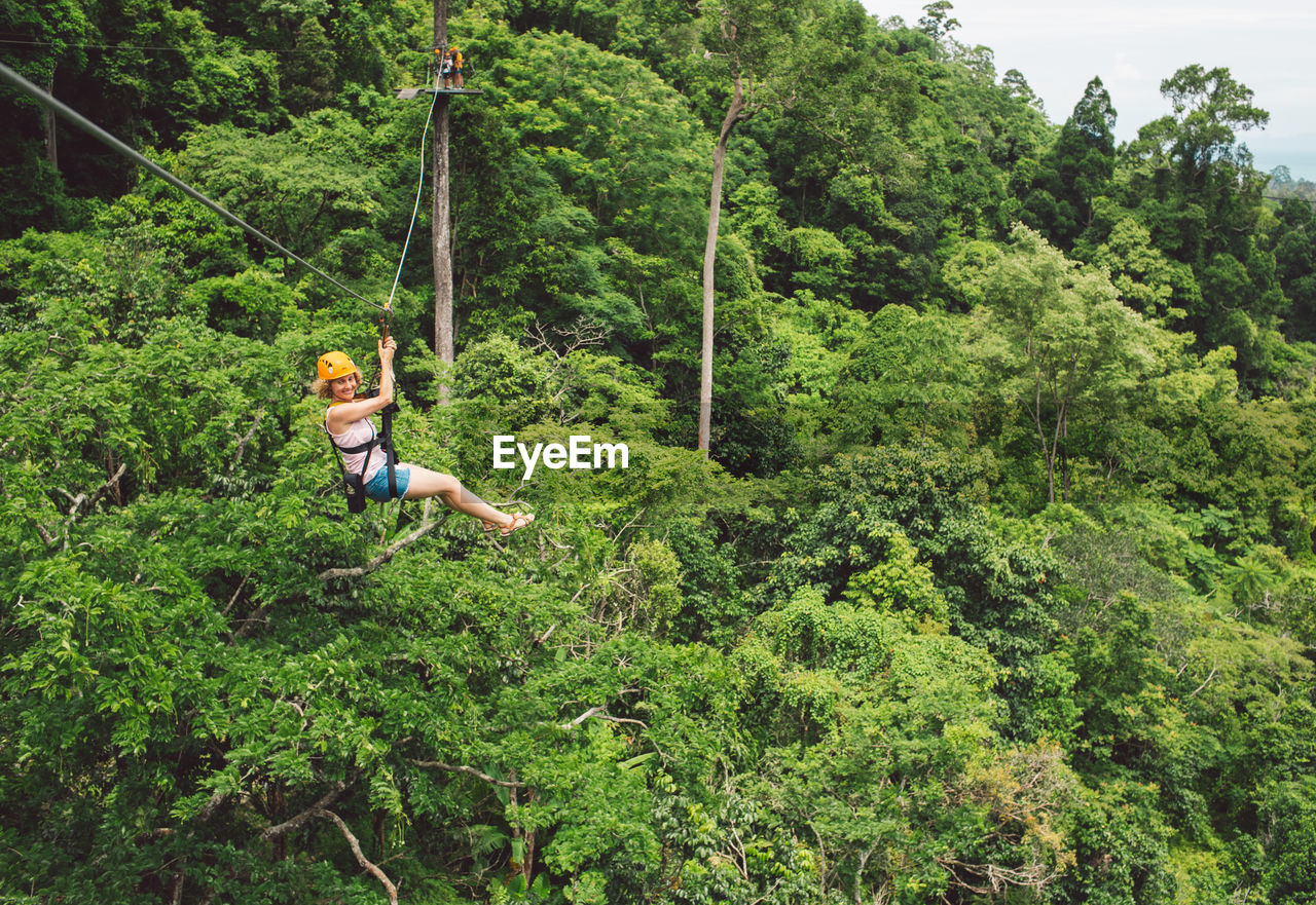 Full length of woman ziplining in forest