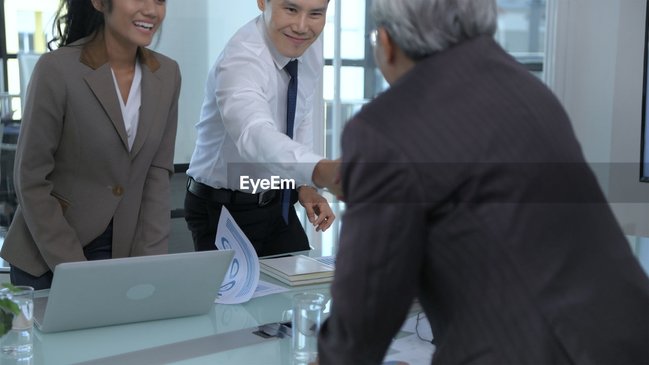 Business peoples shaking hands over table at office