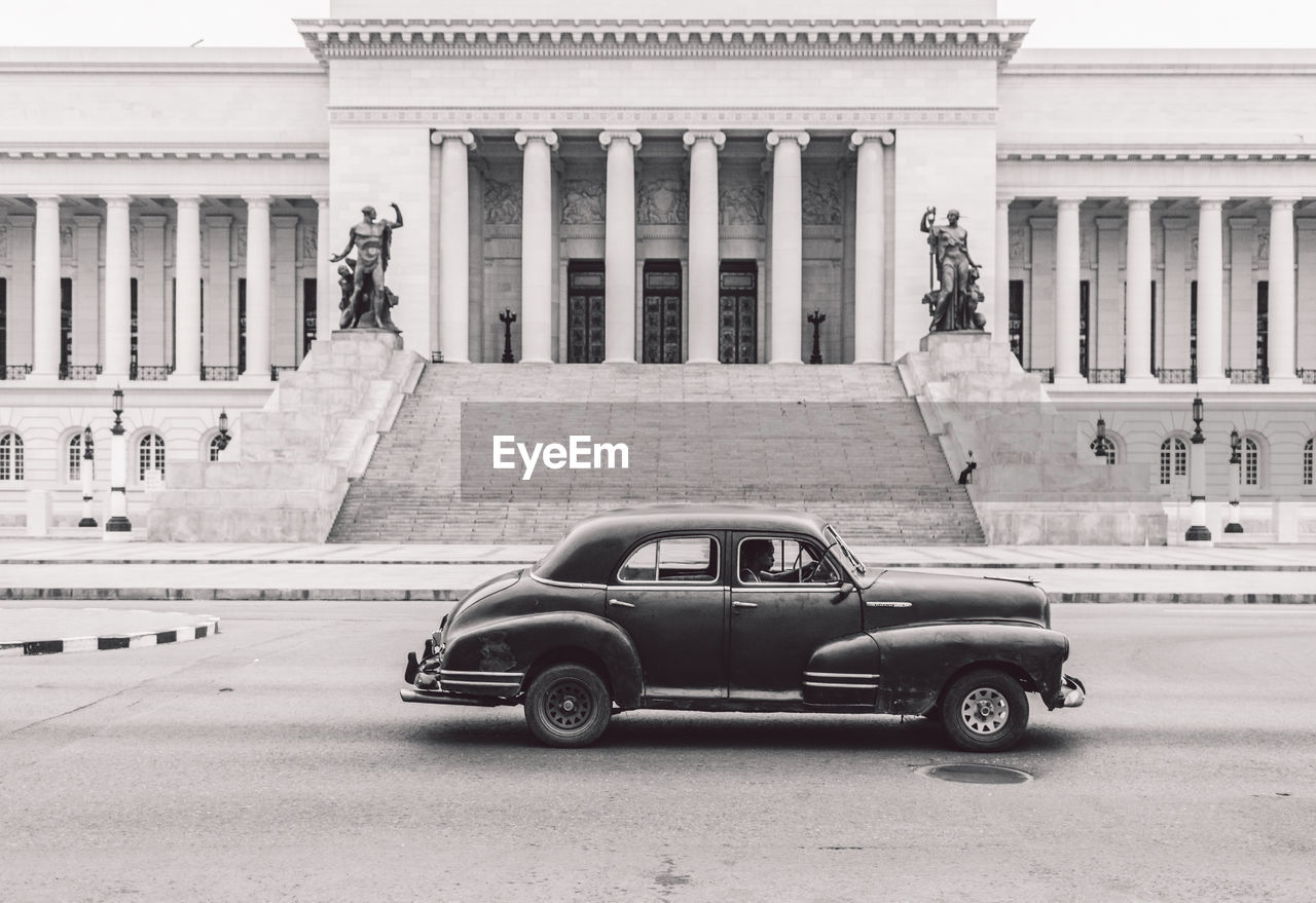 VINTAGE CAR ON STREET AGAINST BUILDING