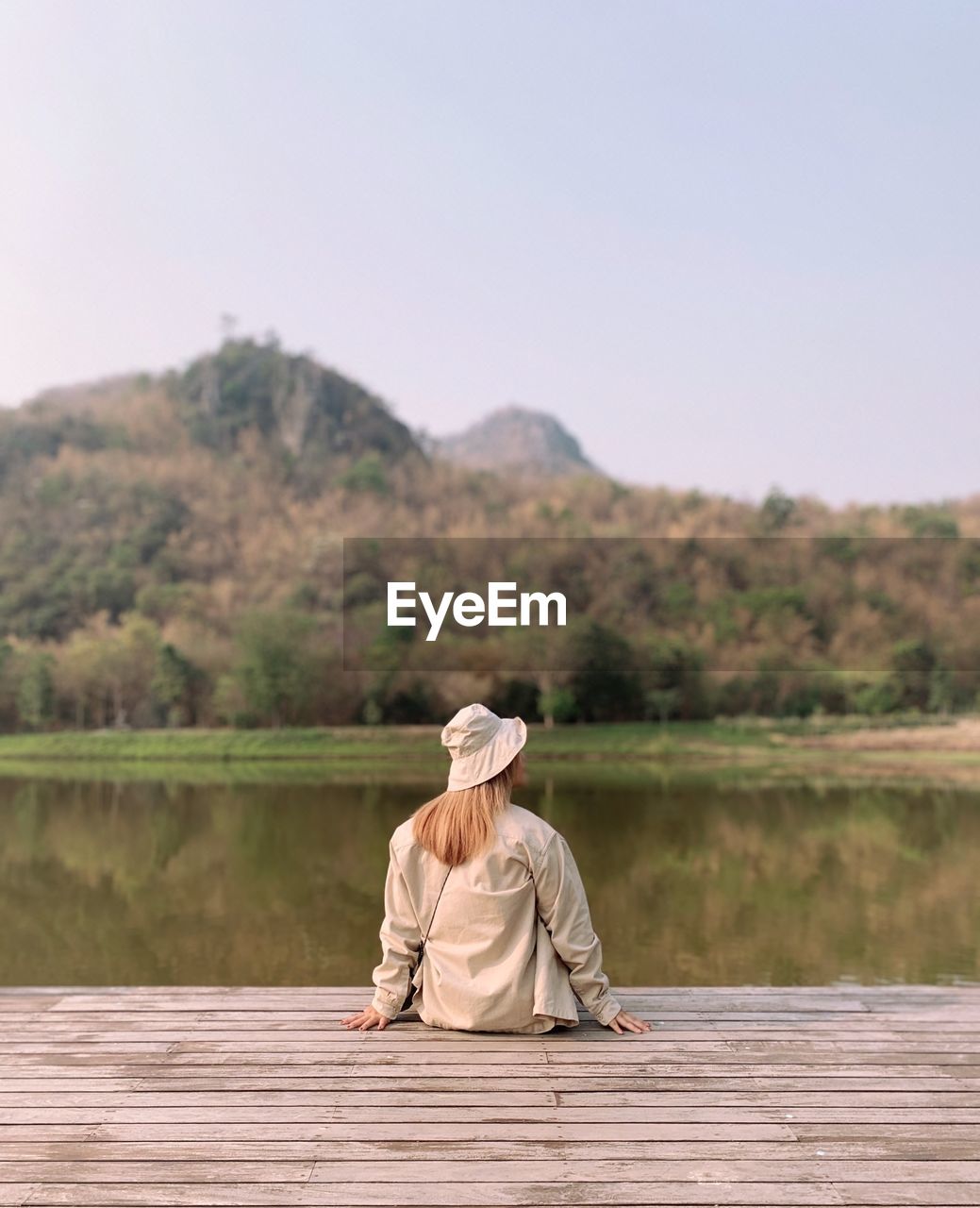 Woman sitting by lake against mountain