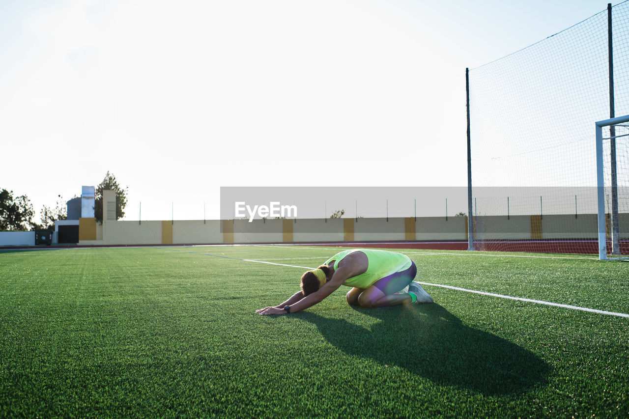 Young man practices stretching on the grass after his daily training