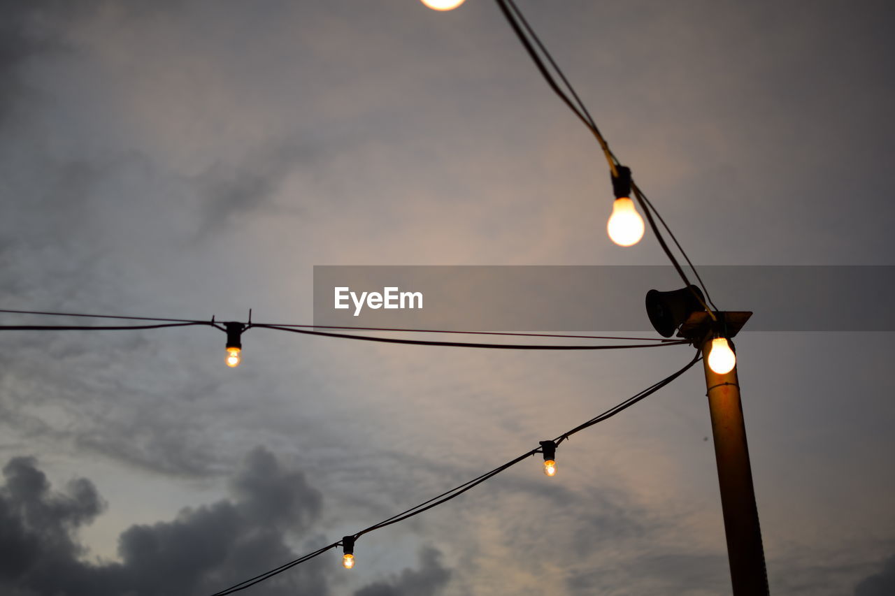 Low angle view of illuminated street lights against sky