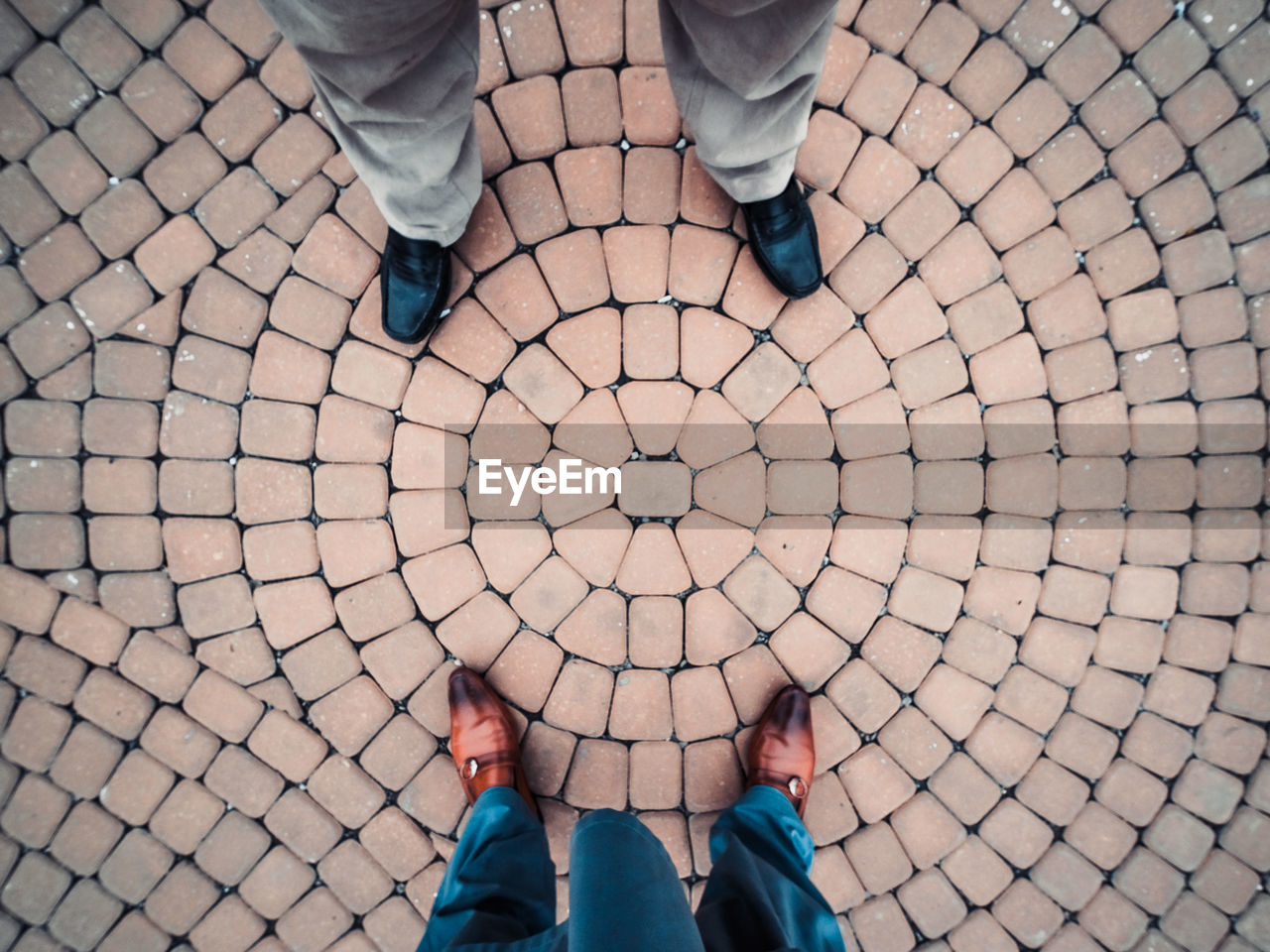 View from above of two men standing on a circular arranged pavement