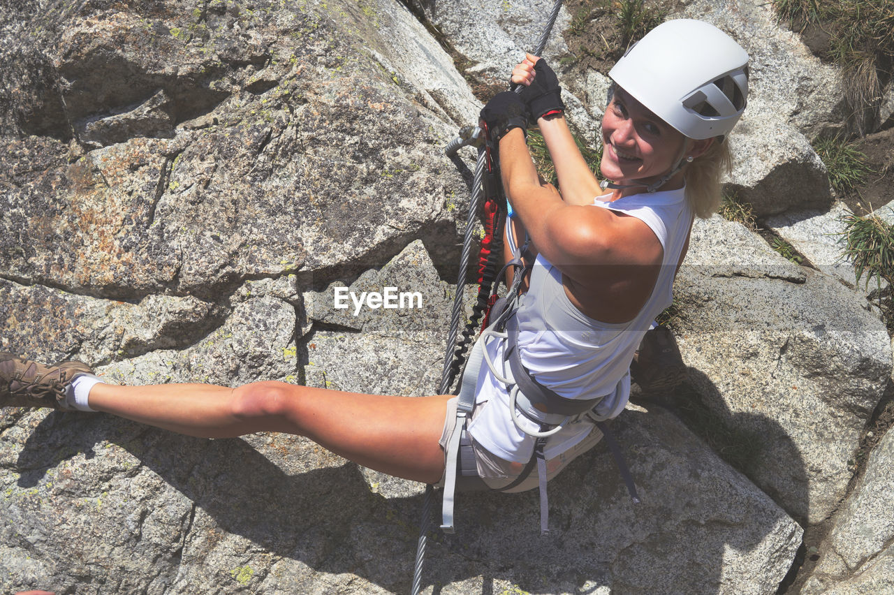 High angle portrait of young woman climbing rock