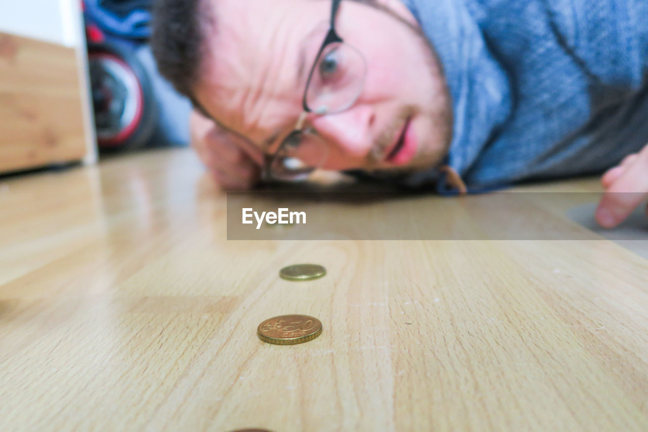 Portrait of man looking at coins on hardwood floor