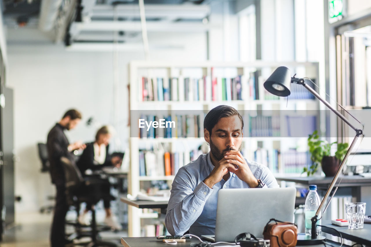 Worried businessman looking at laptop while sitting in office