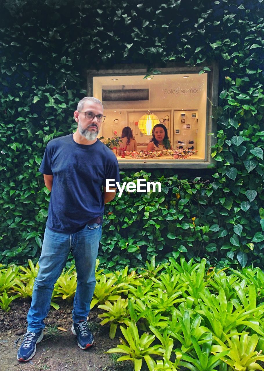 MAN STANDING AGAINST PLANTS