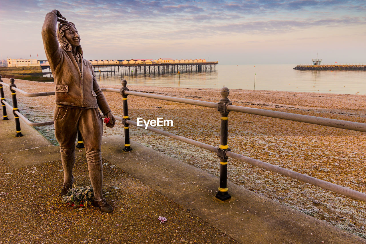 WOMAN STANDING BY RAILING AGAINST SEA AGAINST SKY