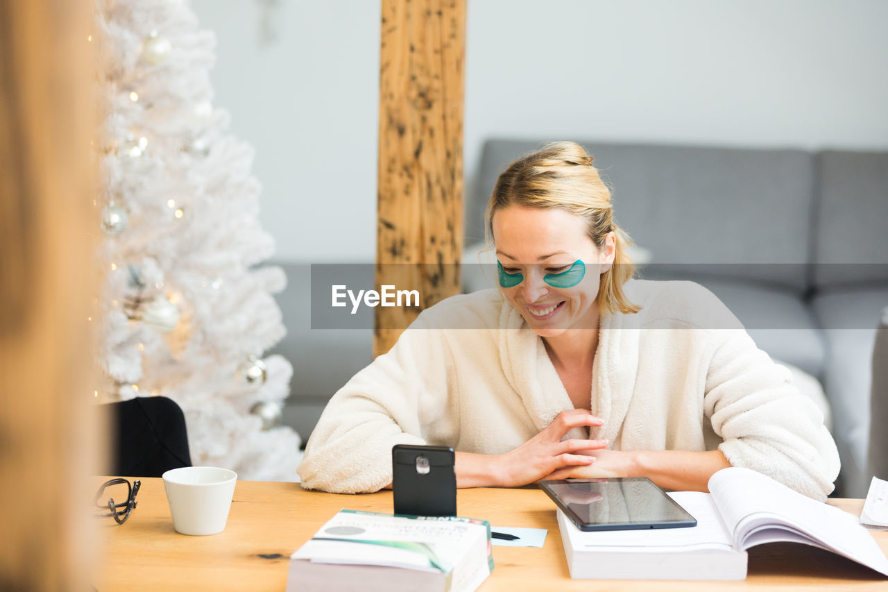 Businesswoman using digital tablet at home by christmas tree