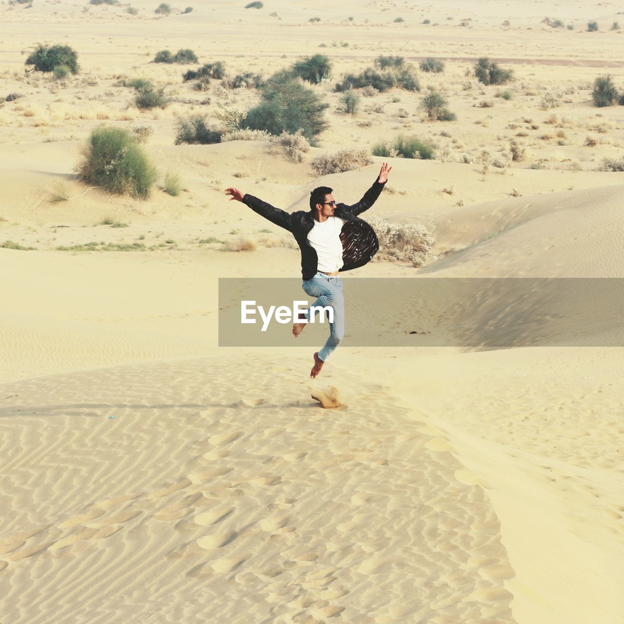 Full length of man jumping over sand at beach