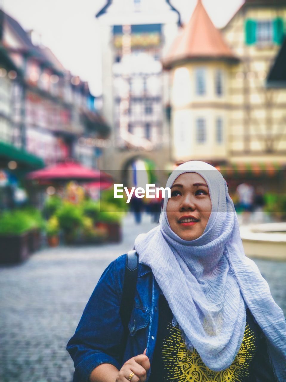 Woman in hijab looking up in city