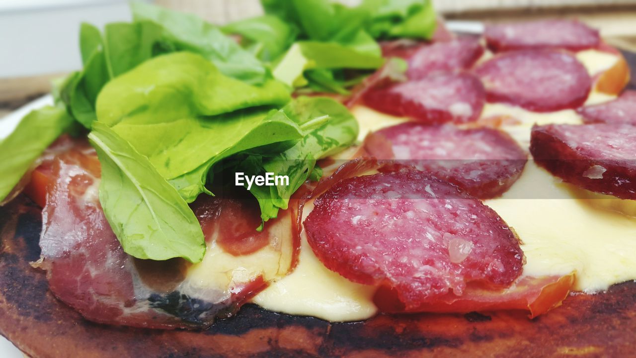 Close-up of pizza with salami and arugula