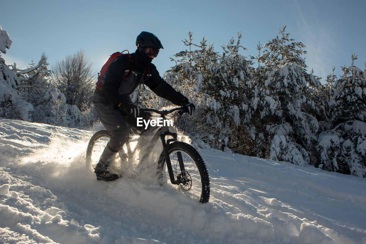 side view of man riding bicycle on snow covered field