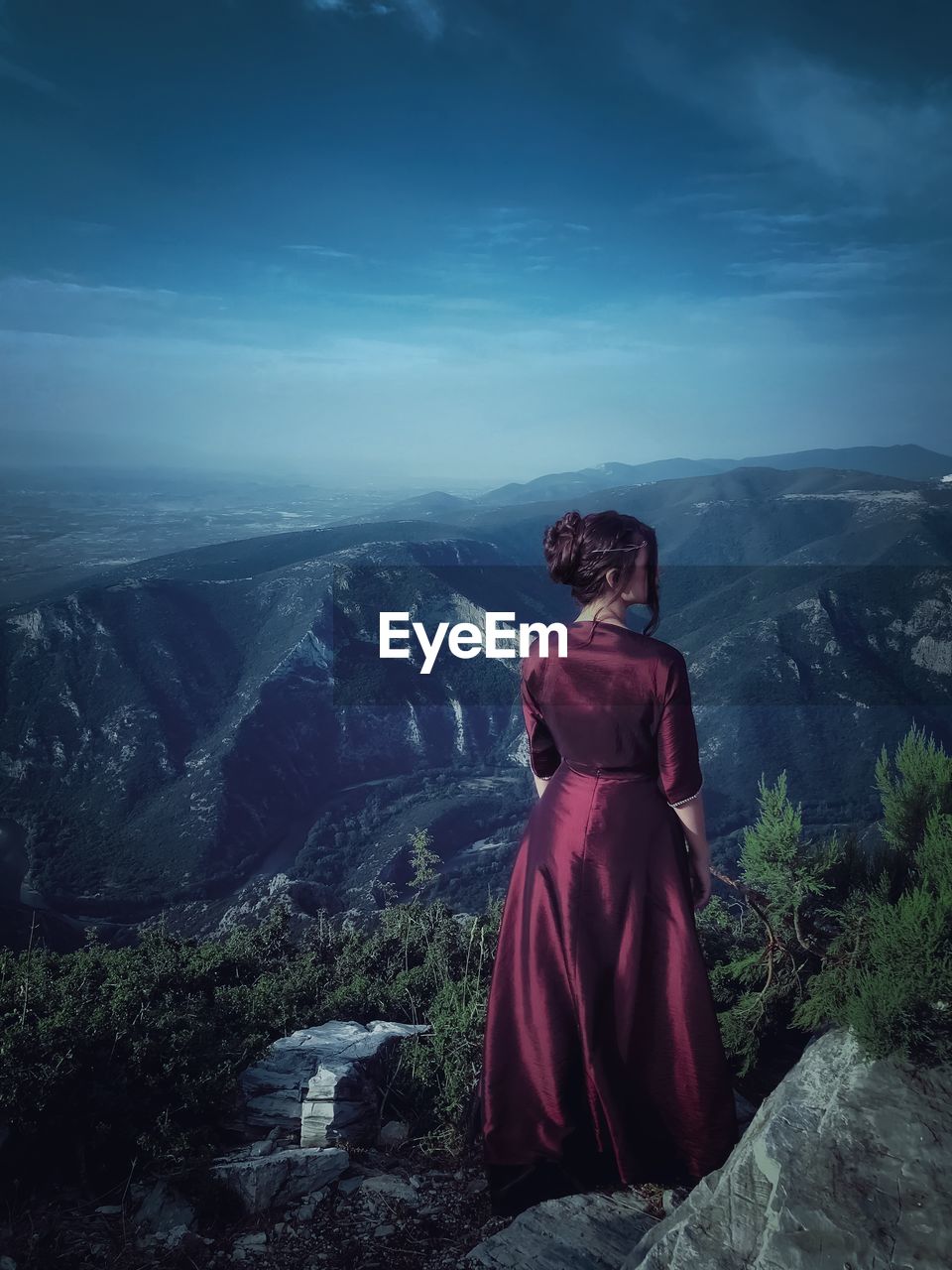 Rear view of woman standing on cliff against sky