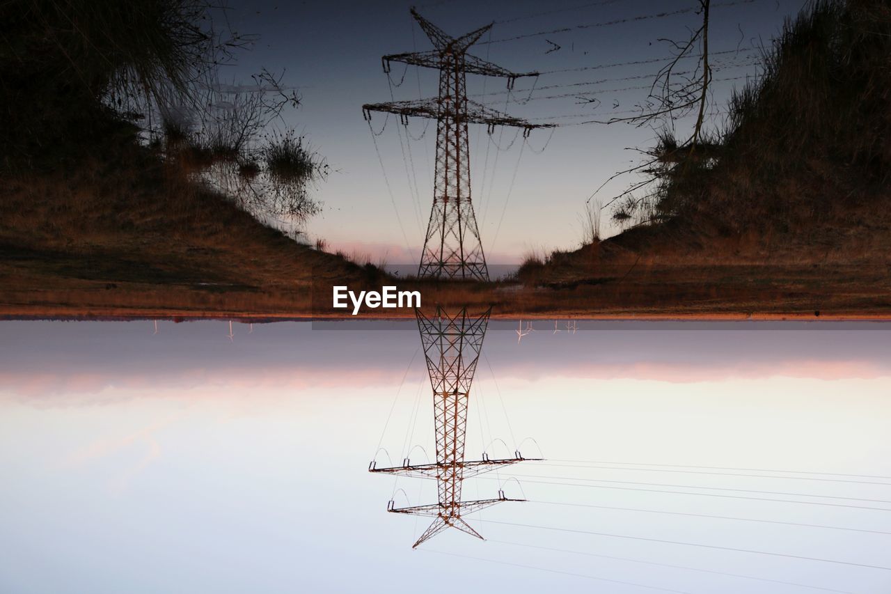 ELECTRICITY PYLON BY LAKE AGAINST SKY