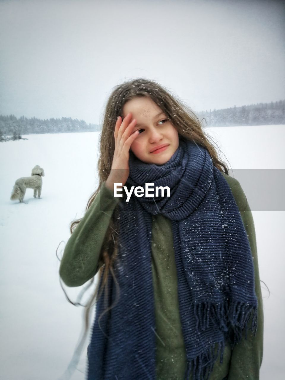 Girl wearing warm clothing looking away while standing in snow