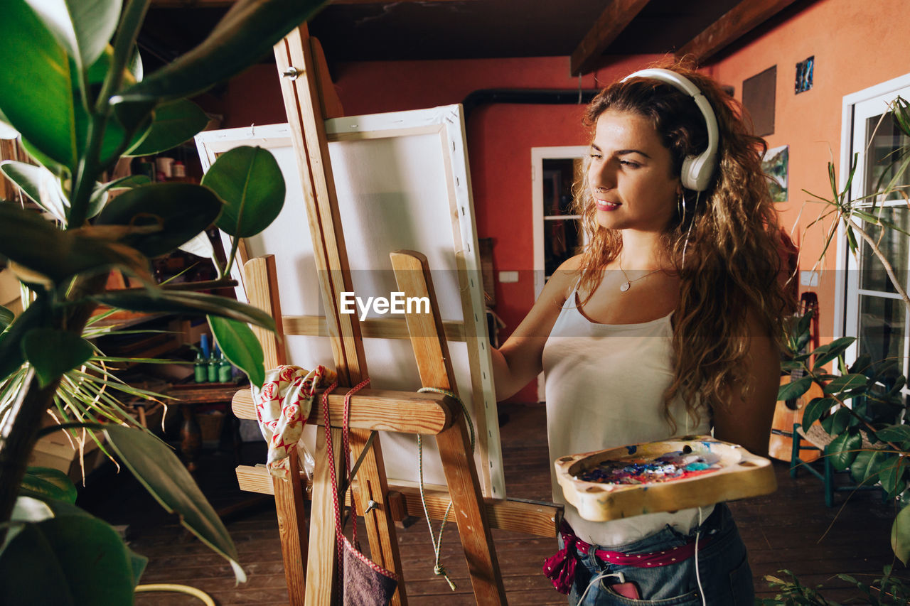 Young woman painting on easel