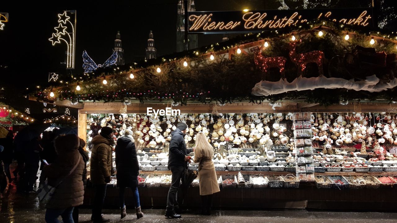 GROUP OF PEOPLE AT ILLUMINATED MARKET