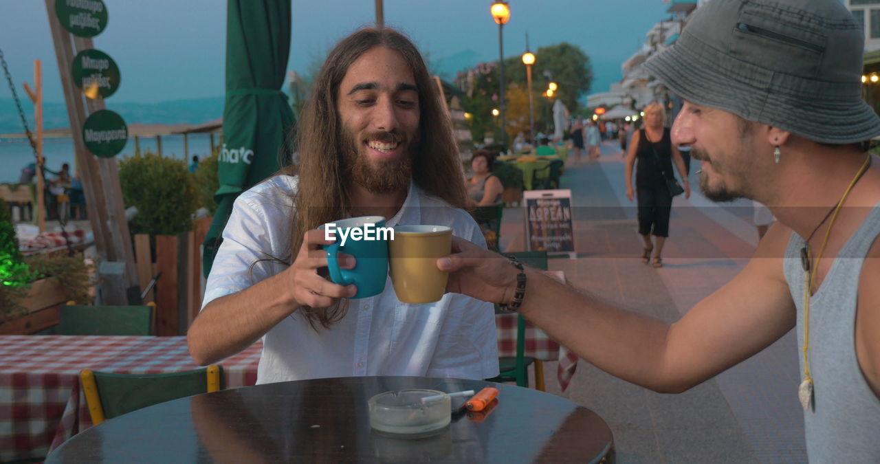 PORTRAIT OF A SMILING YOUNG MAN WITH DRINK