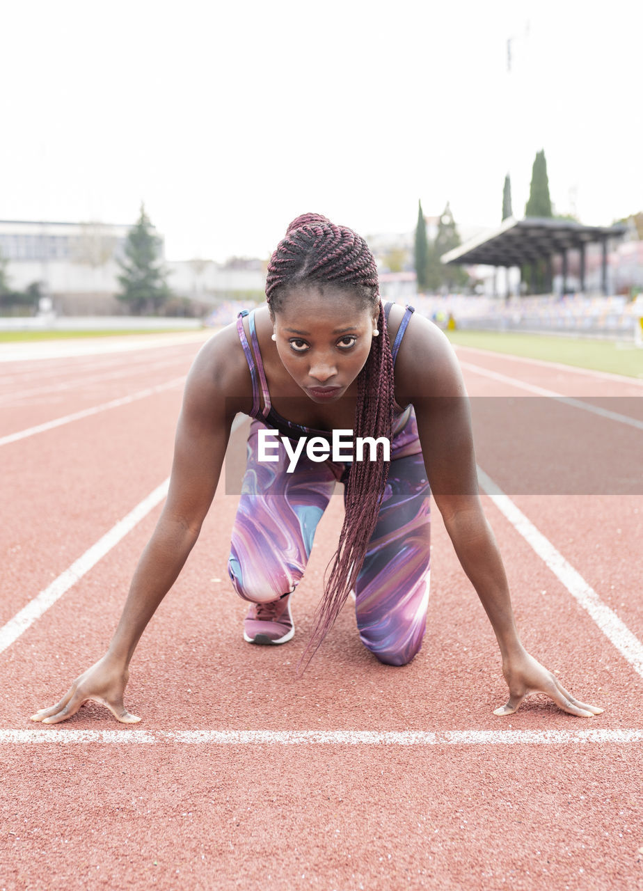 Confident sportswoman on starting line at sports court